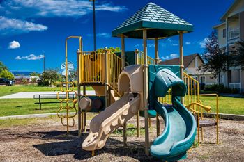A playground with a green slide and a yellow structure.